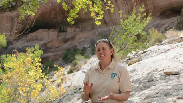 A women in a BLM shirt speaking in front of a brush covered landscape in Bears Ears National Monument.