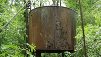 A hulking, rusted oil tank in overgrown forest in western Pennsylvania